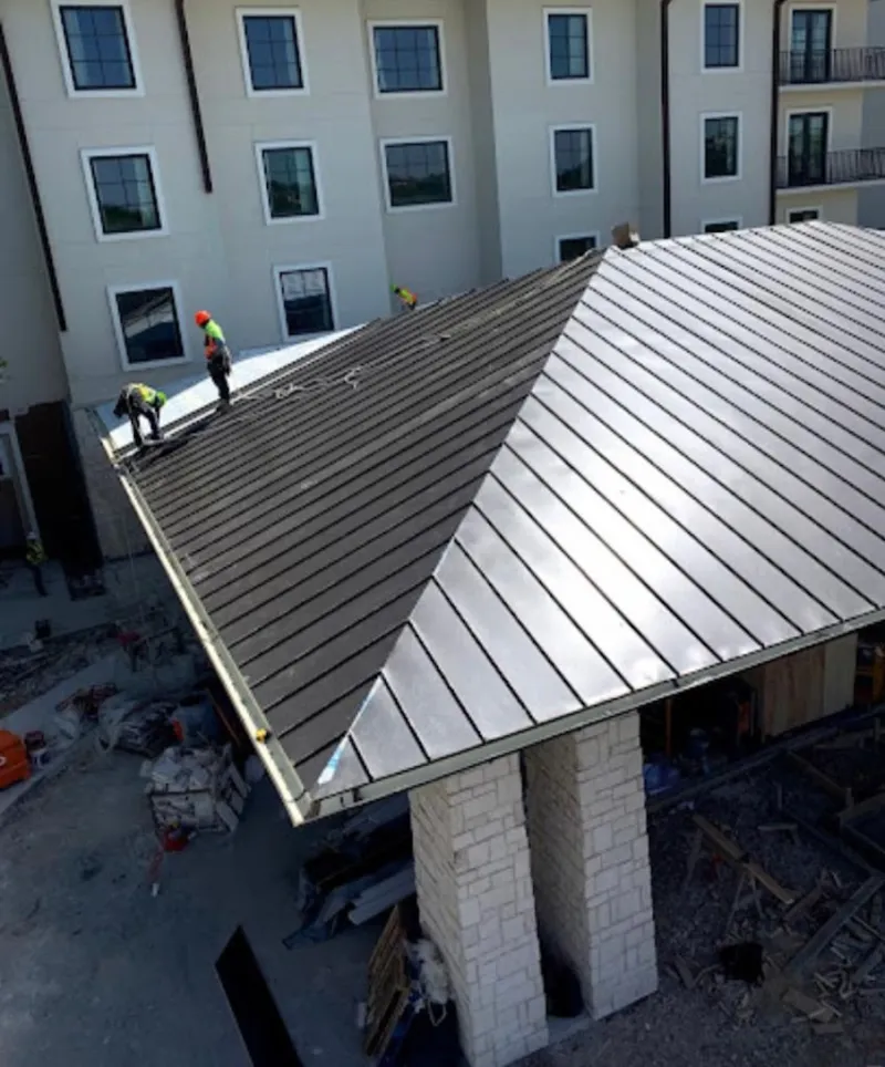 Crew installing standing seam metal roof panels on a commercial project in Napoleon